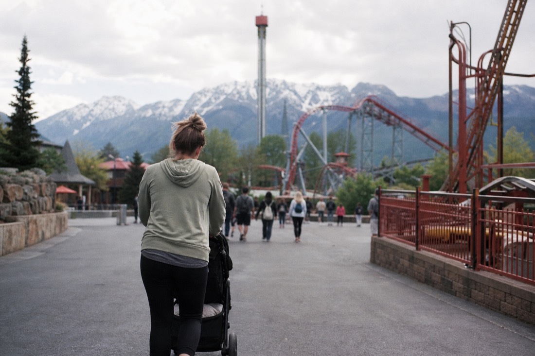 Parent pushing a stroller through the park with the mountain ahead