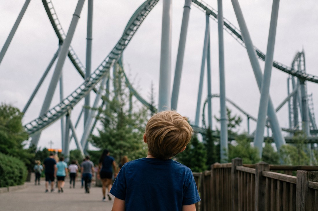Child looking up at the towering coaster structure from the path