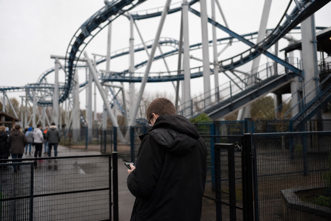 Visitor checking the live schedule on a phone near a Fuji-Q Highland ride