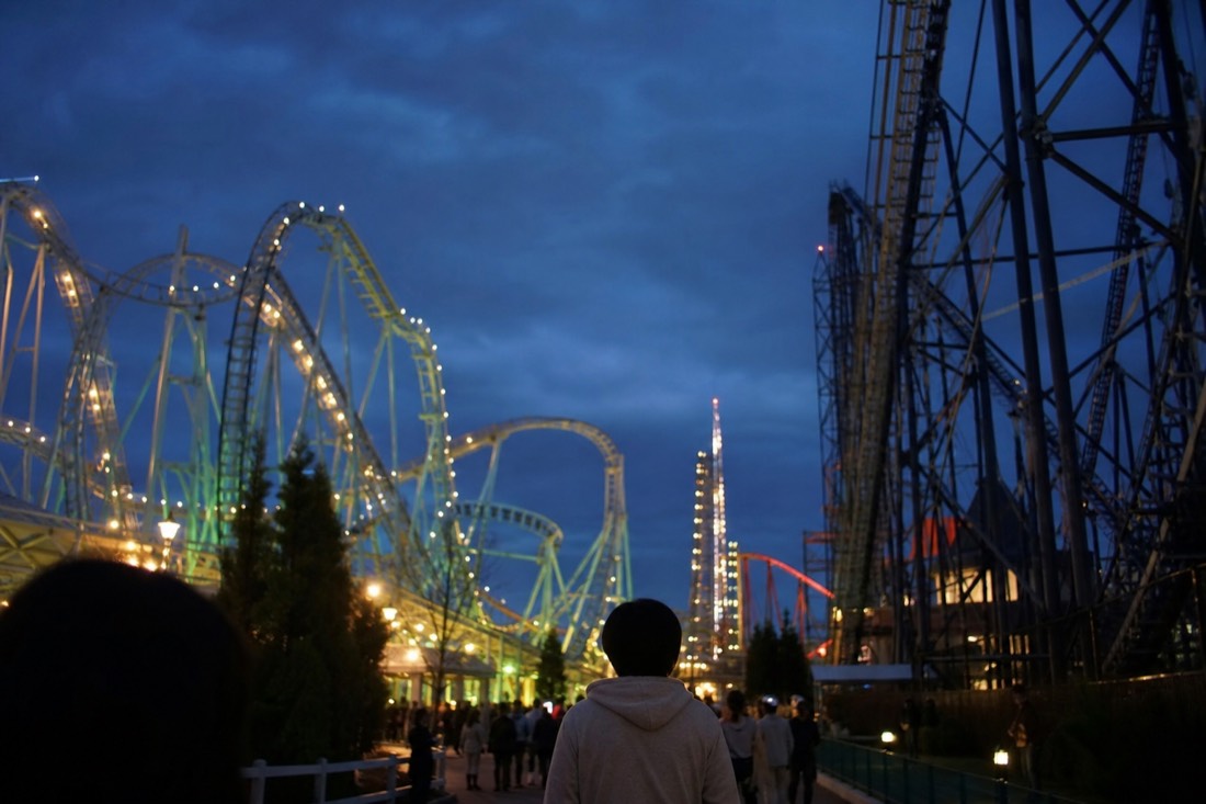 Fuji-Q Highland at dusk with illuminated coaster structures on an extended-hours evening