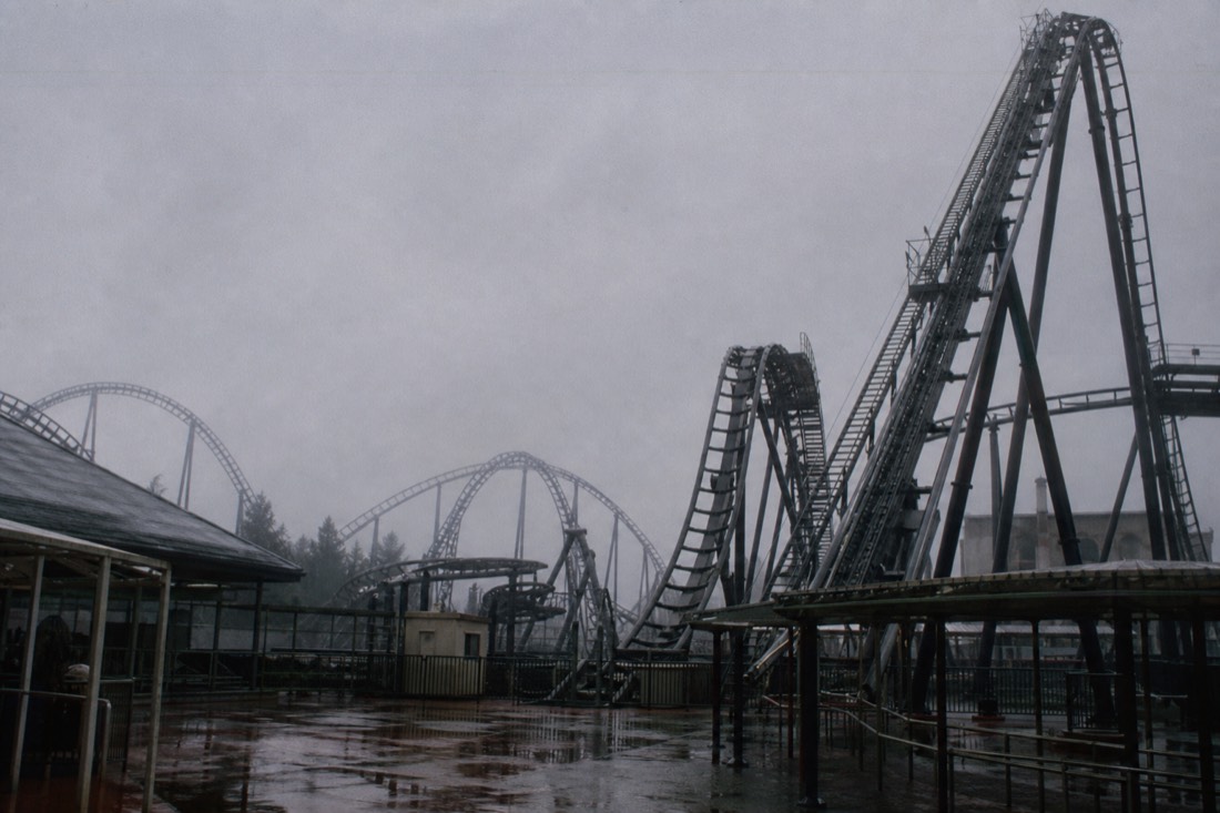 A tall Fuji-Q Highland coaster idle and empty under a grey rainy sky